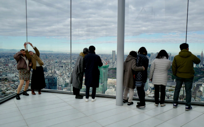 Visitors enjoying the view from SHIBUYA SKY observation deck in Tokyo.