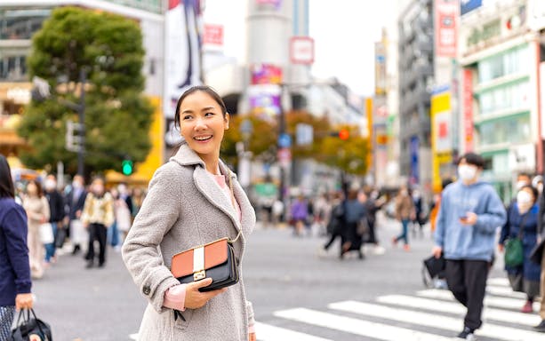Person smiling at Shibuya Crossing in Tokyo during a personalized photoshoot.