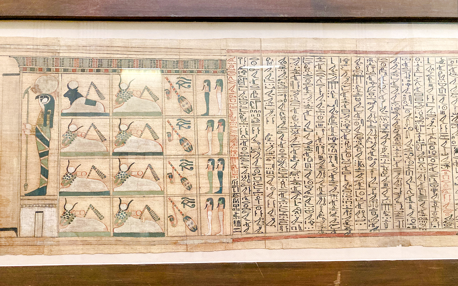 Ancient Egyptian papyrus with hieroglyphs and illustrations of deities and symbols.