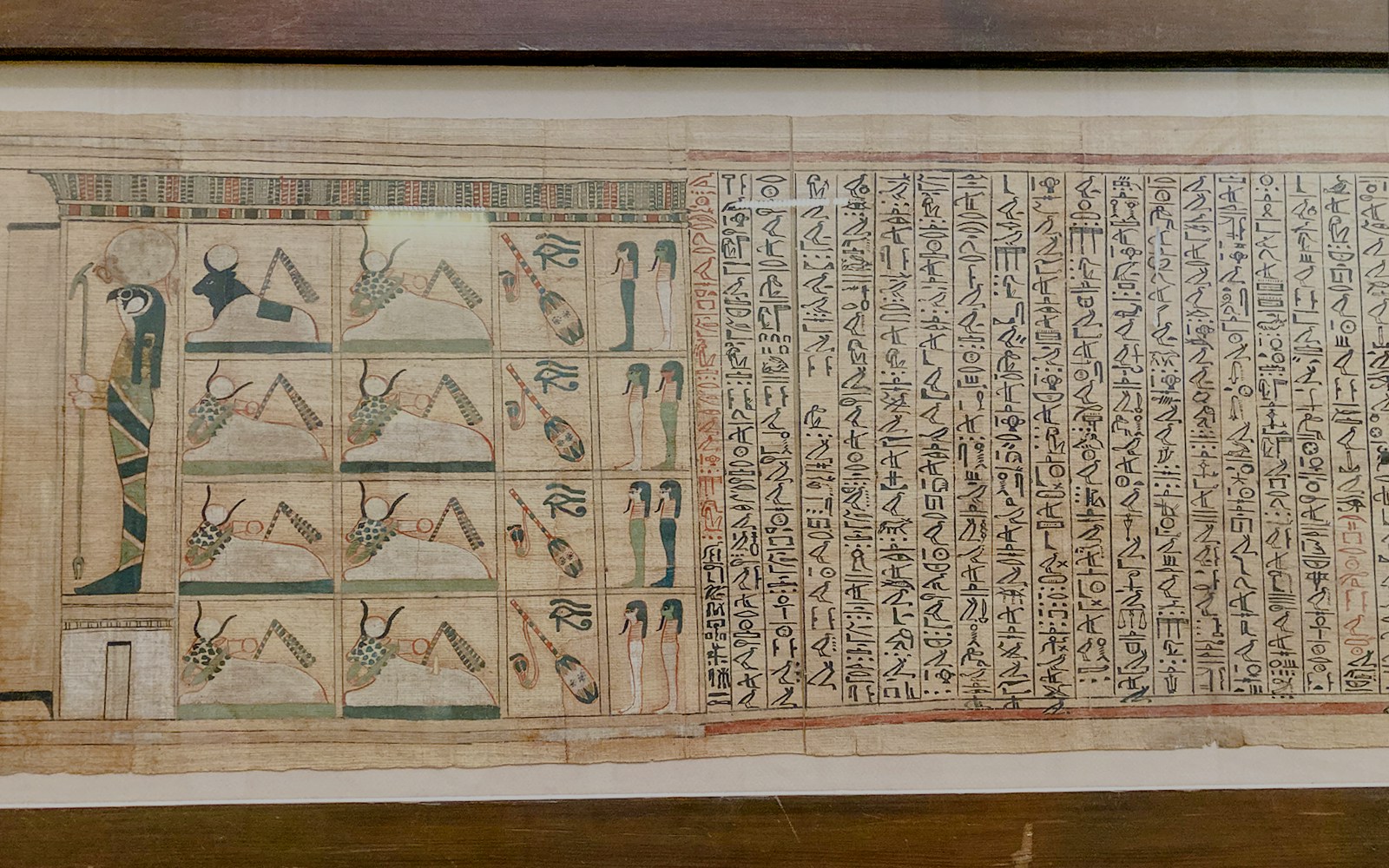 Ancient Egyptian papyrus with hieroglyphs and illustrations of deities and symbols.