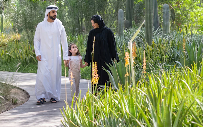 Family walking on a path surrounded by greenery at Al Noor Island, Sharjah.