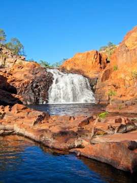 Waterfall cascading over red rocks in Kakadu National Park, Australia.
