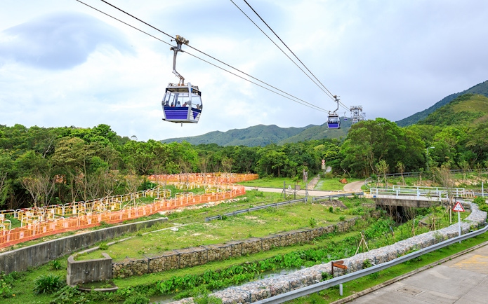 Ngong Ping Cable Car over lush landscape with mountains in the background, Hong Kong.