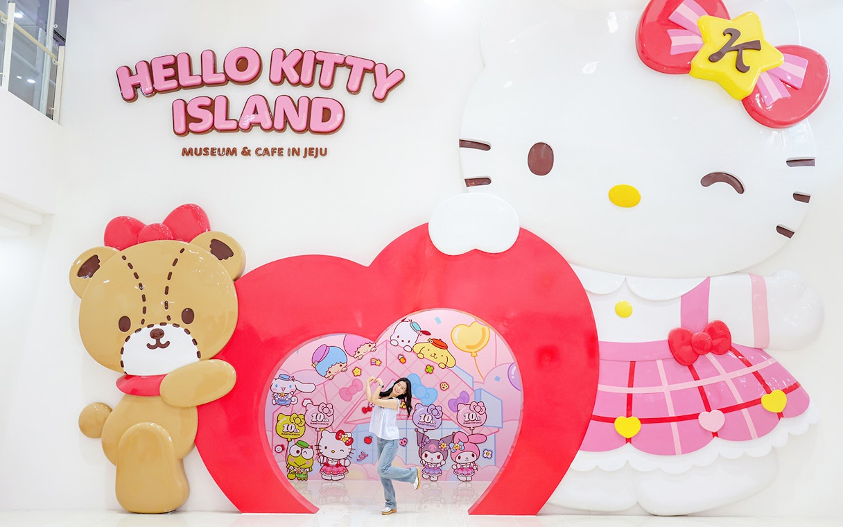 Tourist posing at Hello Kitty Island entrance in Jeju.