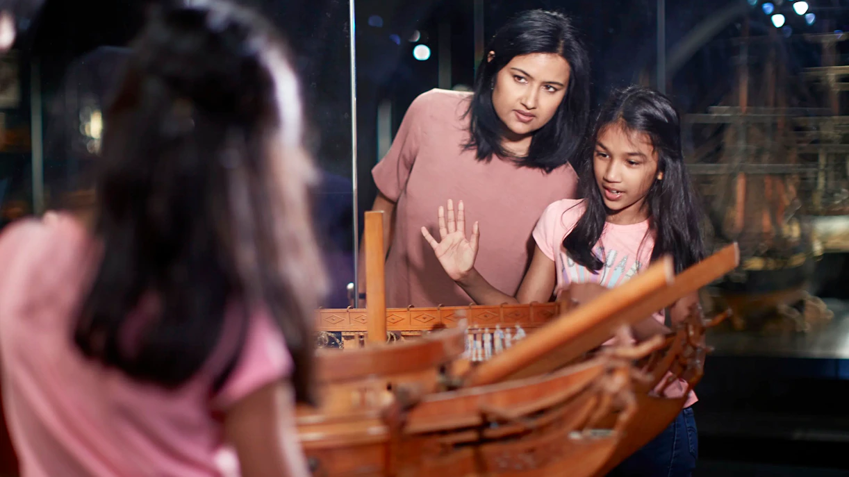 Visitors examining Dutch East India Company ship model at Rijksmuseum, Amsterdam.