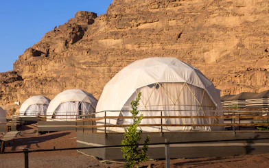 Geodesic domes at a camp in Wadi Rum Desert, Jordan with rocky cliffs in the background.