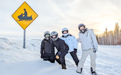 Group of people in snow gear next to snowmobile sign, Fairbanks, Alaska.