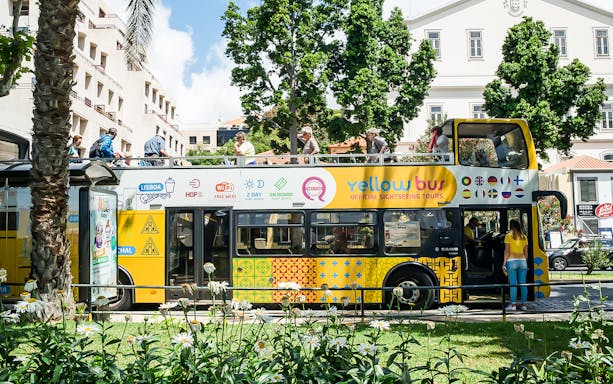 Open-top sightseeing bus in Madeira with tourists on board.