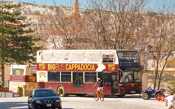 Open-top tour bus in Cappadocia with scenic rock formations in the background.