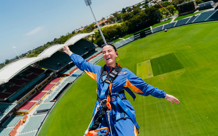 Adelaide Oval roof climb participant smiling with stadium view.