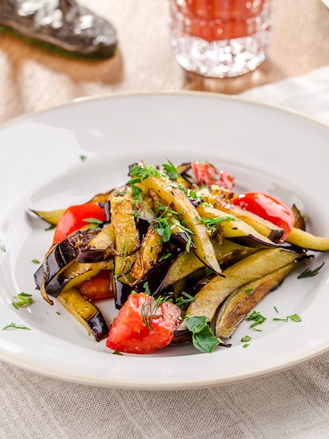 Grilled vegetables with herbs on a white plate for lunch.