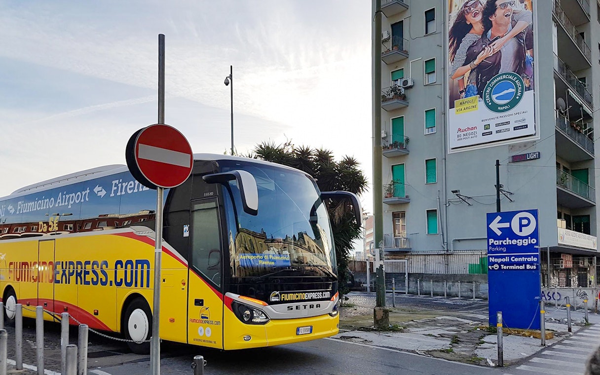 Fiumicino Express bus parked near Naples Centrale sign.