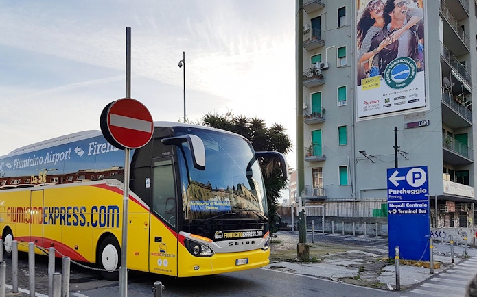 Fiumicino Express bus parked near Naples Centrale sign.