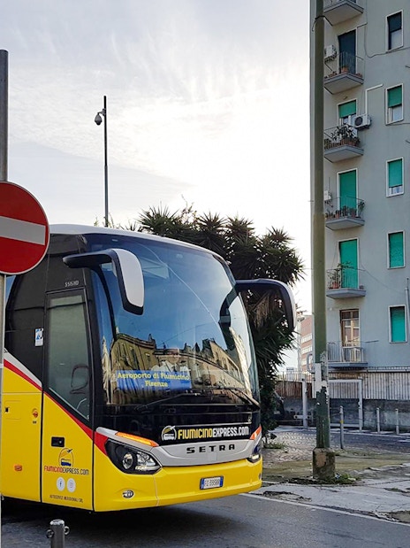 Fiumicino Express bus parked near Naples Centrale sign.