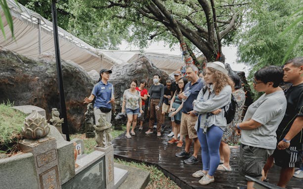 Tour group listens to guide by historic tombstone at Hell's Museum.