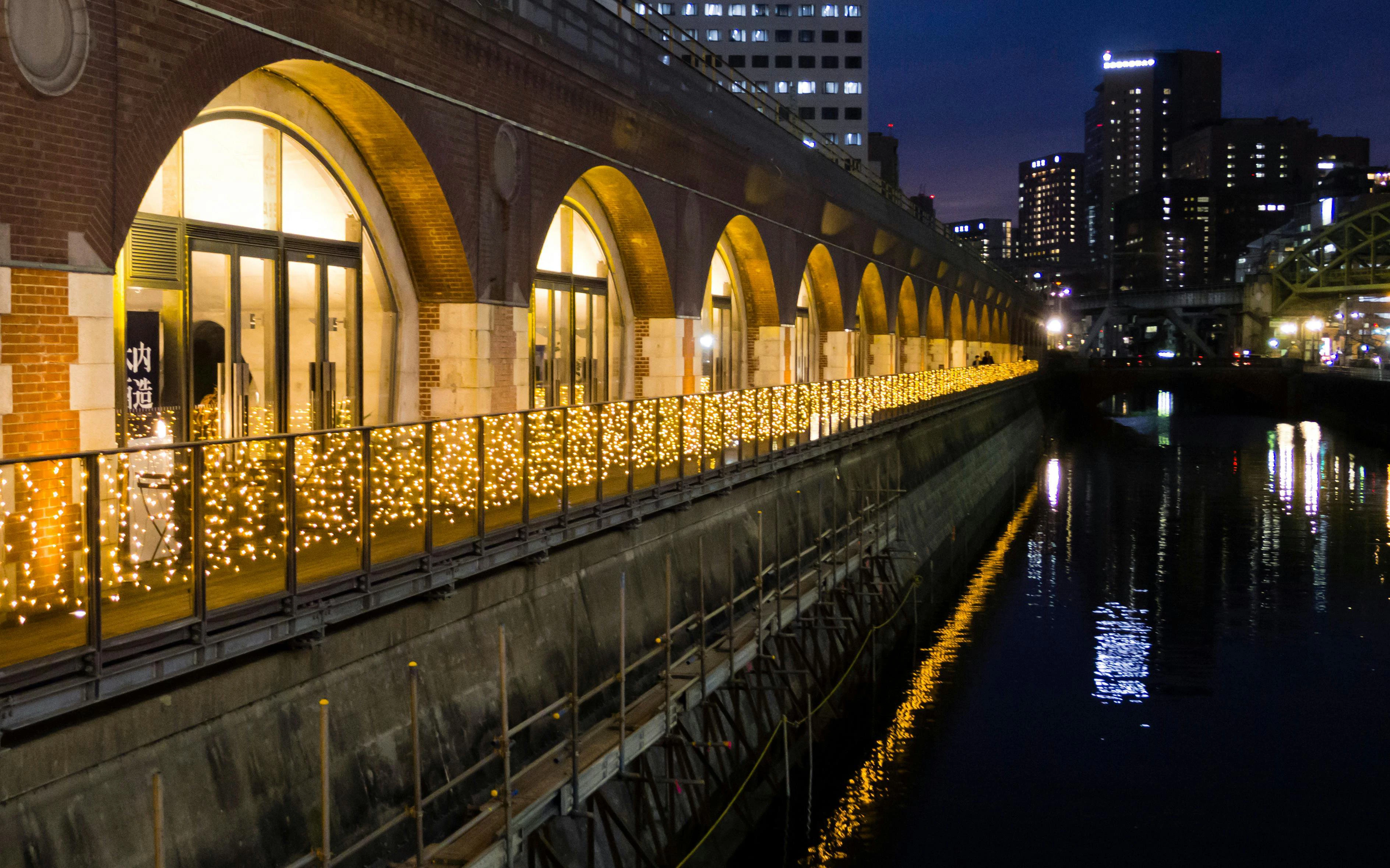 Old Manseibashi Station illuminated by lights along Kanda River in Tokyo at night.