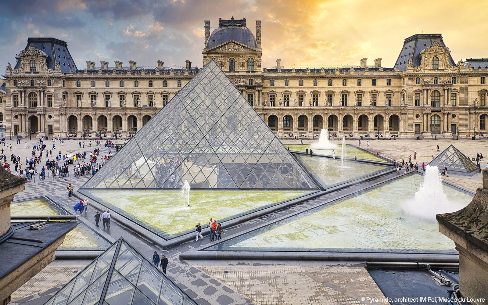 Louvre Museum courtyard with glass pyramid and fountains, Paris, France.