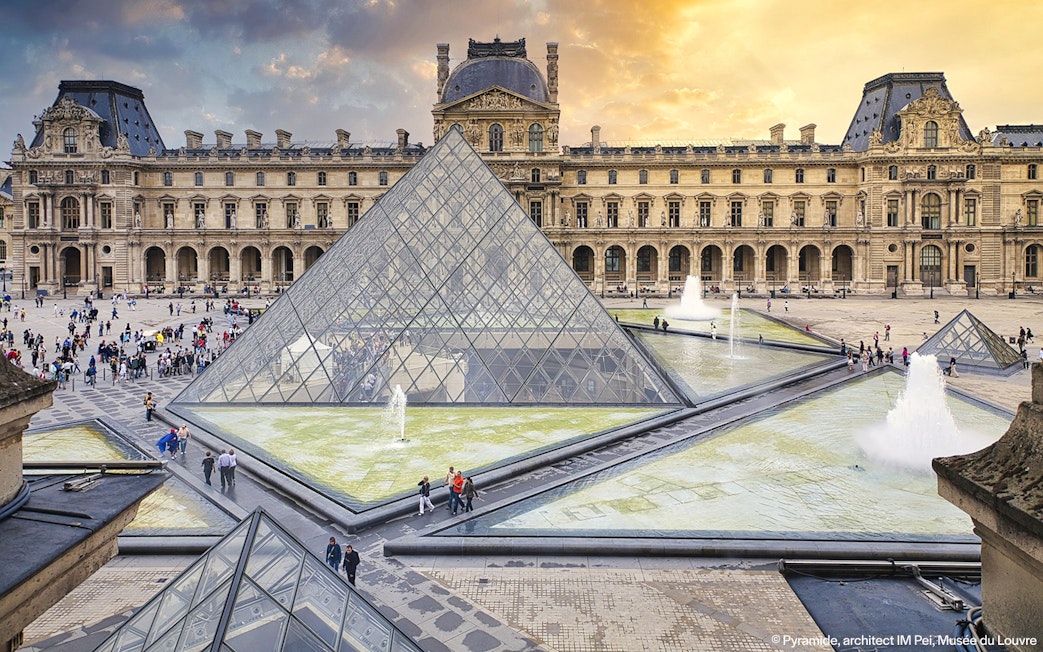 Louvre Museum courtyard with glass pyramid and fountains, Paris, France.