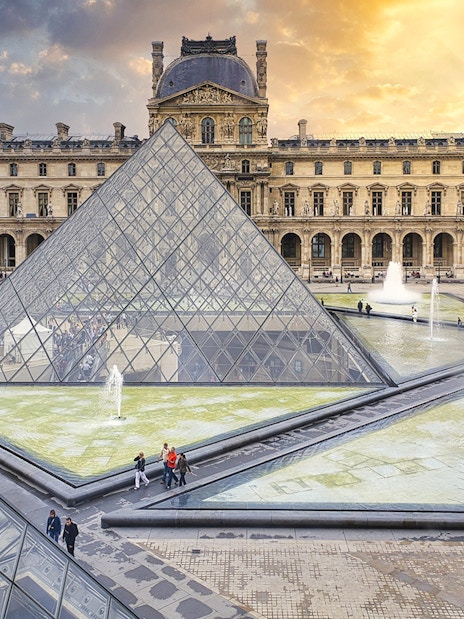 Louvre Museum courtyard with glass pyramid and fountains, Paris, France.