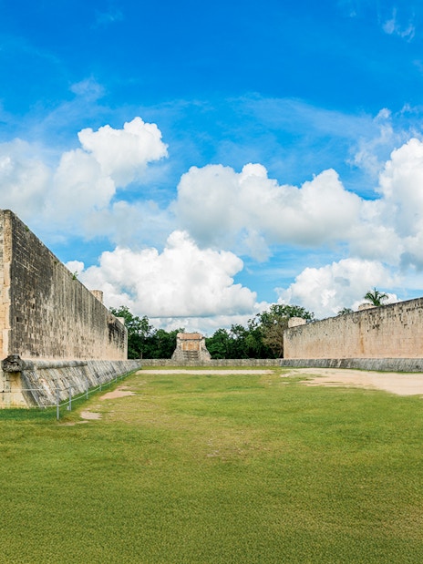 Mayan Ball Game Field at Chichen Itza with ancient stone walls and grassy court.