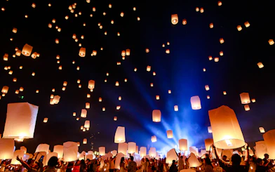 People releasing lanterns into the night sky at Chiang Mai Sky Lanterns Festival 2025.
