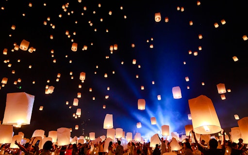 People releasing lanterns into the night sky at Chiang Mai Sky Lanterns Festival 2025.