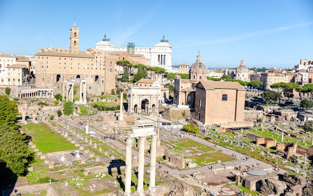 Roman Forum ruins viewed from Palatine Hill, Rome, with ancient columns and historic buildings.