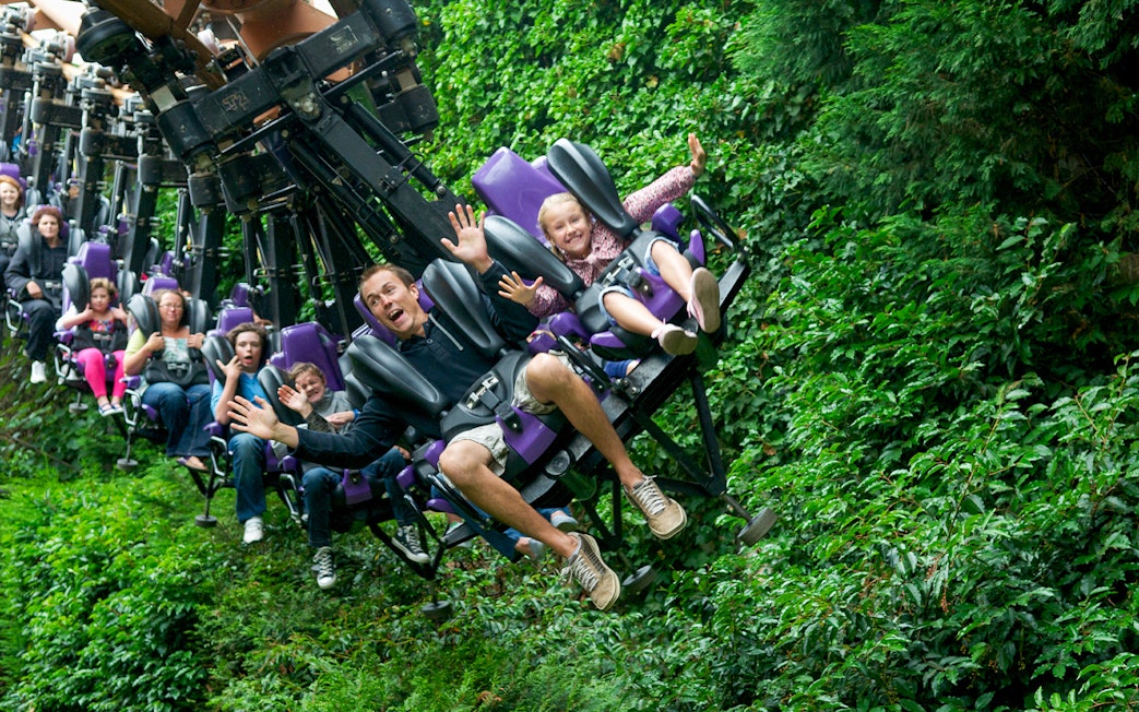 Families enjoying a thrilling rollercoaster ride through lush greenery.