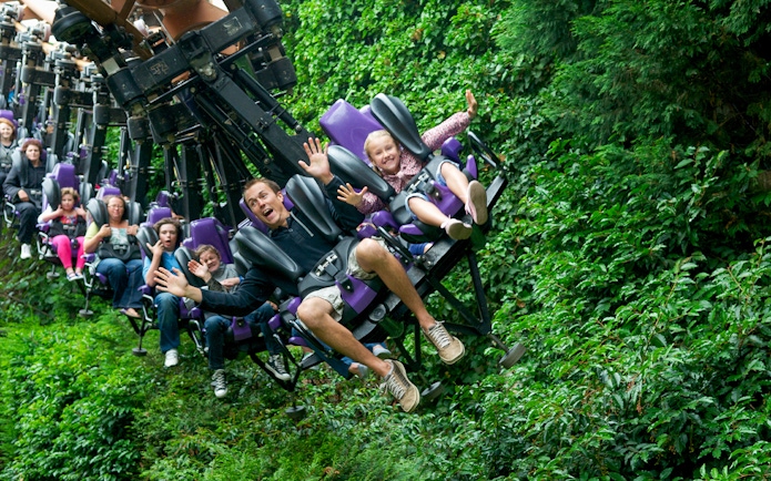 Families enjoying a thrilling rollercoaster ride through lush greenery.