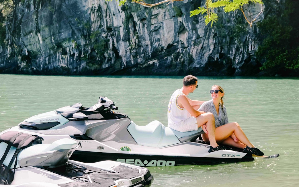 Jet ski on water with two people at Langkawi's UNESCO Kilim Geopark.
