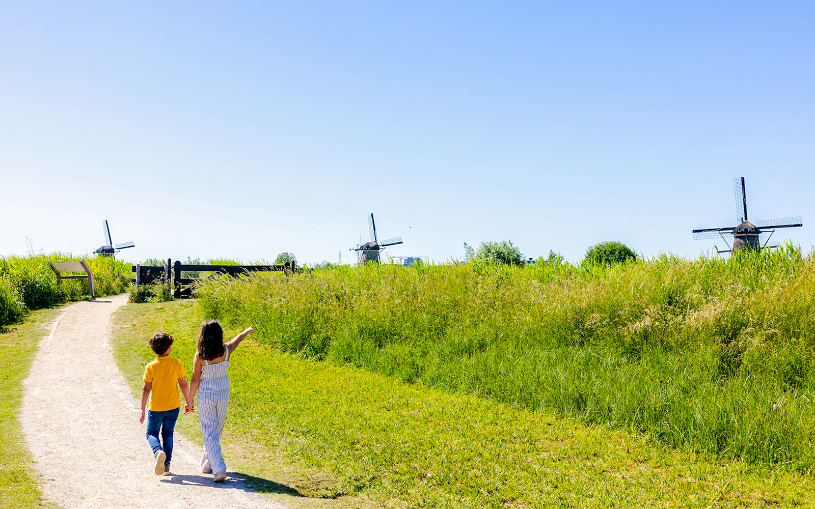 Children walking on a path towards windmills at Kinderdijk, Netherlands.