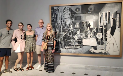 Tourists with guide at Picasso Museum viewing a black and white painting.