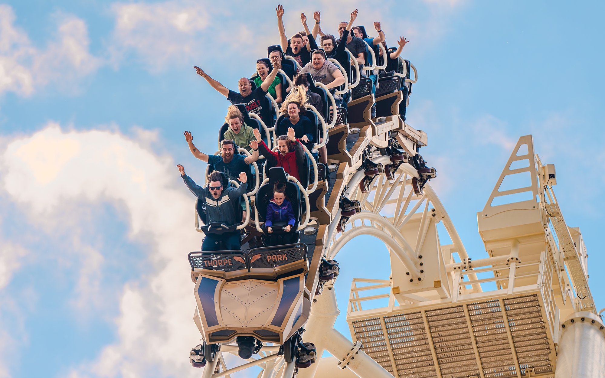 Riders with raised arms on THE SWARM roller coaster at Thorpe Park Resort, Surrey, UK.