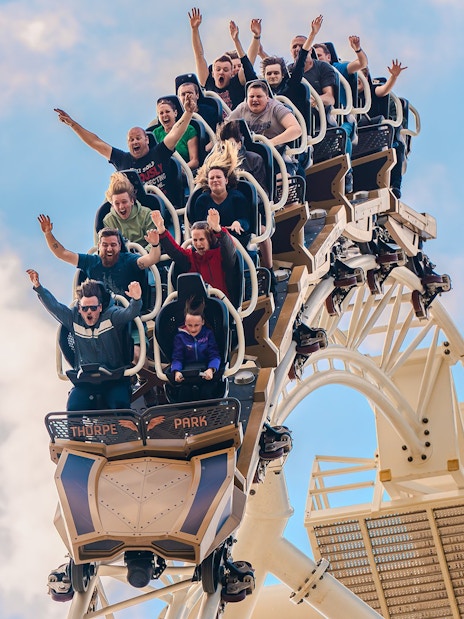 Riders with raised arms on THE SWARM roller coaster at Thorpe Park Resort, Surrey, UK.