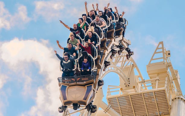 Riders with raised arms on THE SWARM roller coaster at Thorpe Park Resort, Surrey, UK.