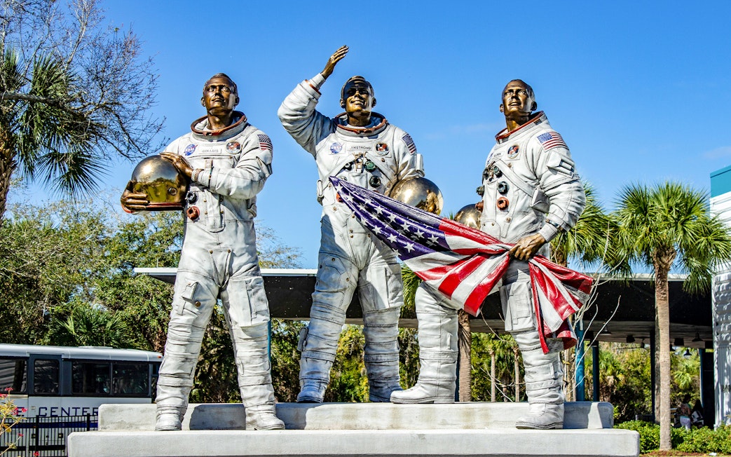 Statues of astronauts holding helmets and flag at Kennedy Space Center, USA.