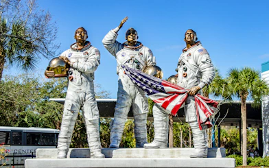 Statues of astronauts holding helmets and flag at Kennedy Space Center, USA.