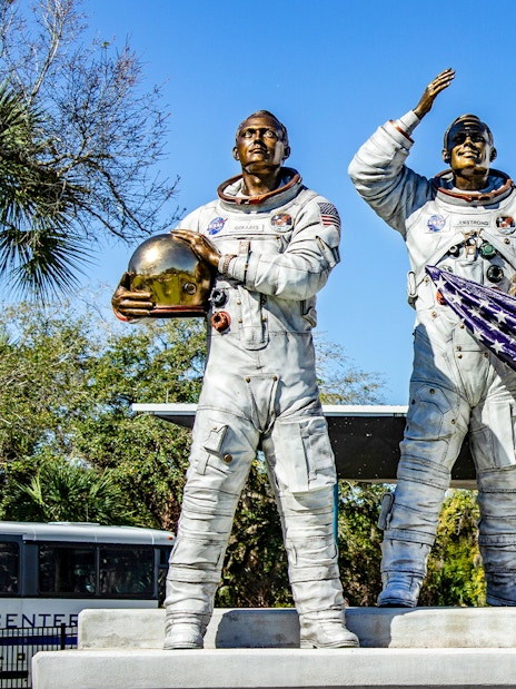 Statues of astronauts holding helmets and flag at Kennedy Space Center, USA.