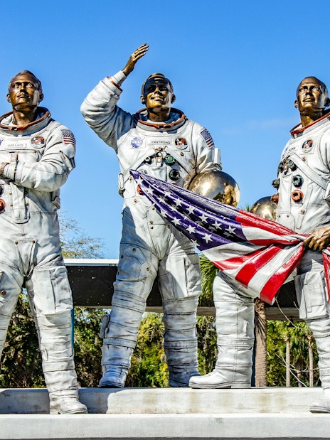 Statues of astronauts holding helmets and flag at Kennedy Space Center, USA.
