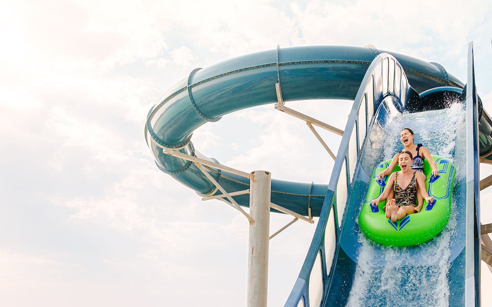 Two people sliding down a water slide at Meryal Waterpark.