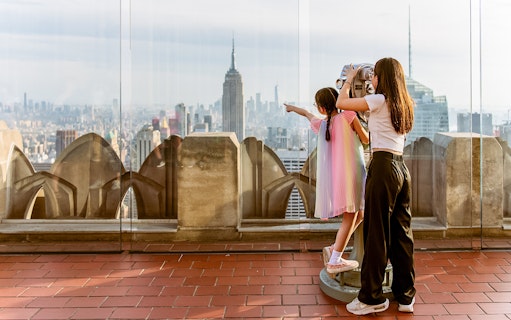 Children using binoculars at Top of the Rock, Rockefeller Center, with New York skyline.