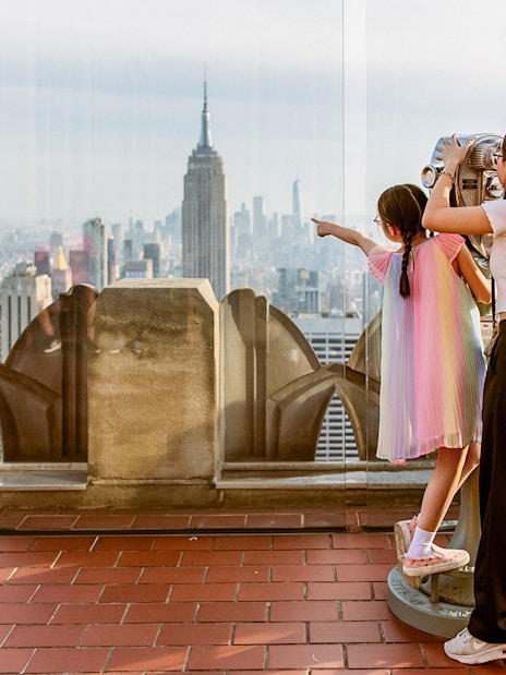 Children using binoculars at Top of the Rock, Rockefeller Center, with New York skyline.