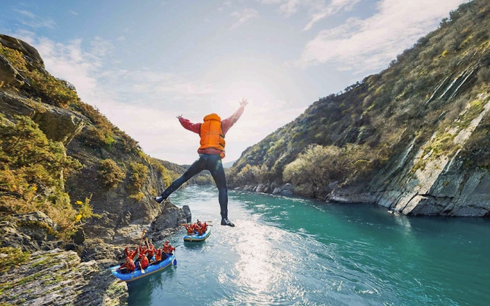 Tourist jumping into Kawarau River during white water rafting adventure.