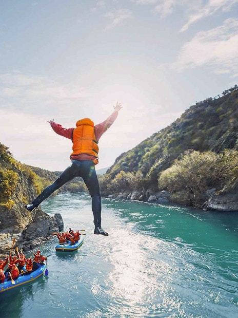 Tourist jumping into Kawarau River during white water rafting adventure.