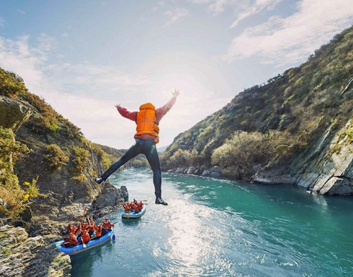 Tourist jumping into Kawarau River during white water rafting adventure.
