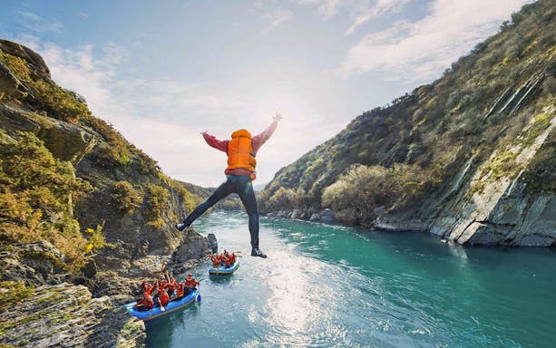 Tourist jumping into Kawarau River during white water rafting adventure.