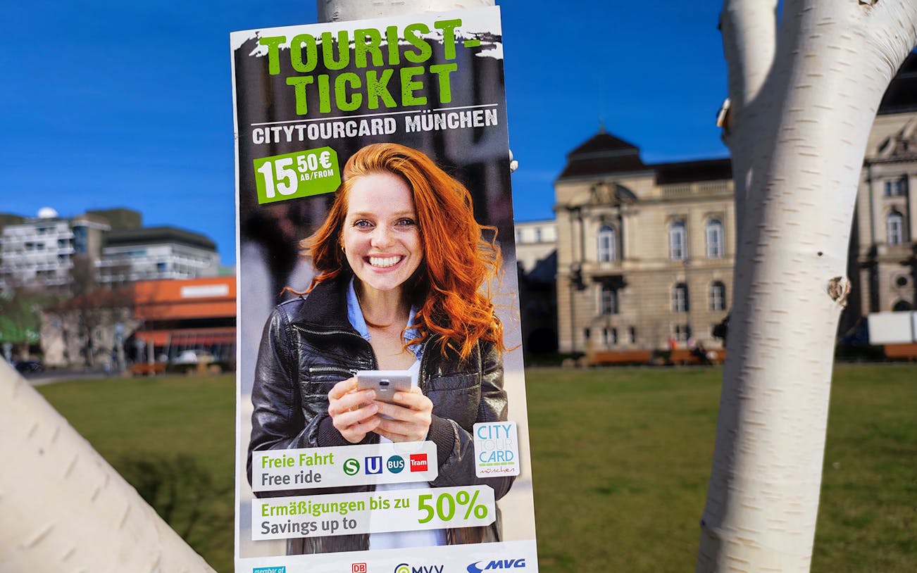 Tourist ticket poster for City Tour Card Munich with historic building in background.