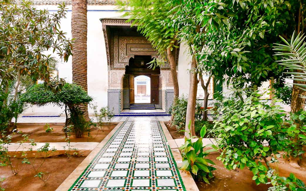 Bahia Palace gardens with tiled pathway and lush greenery in Marrakech, Morocco.