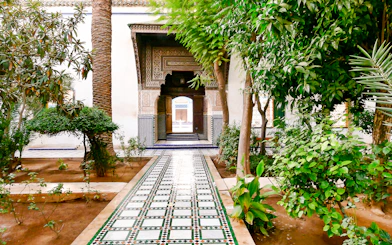 Bahia Palace gardens with tiled pathway and lush greenery in Marrakech, Morocco.