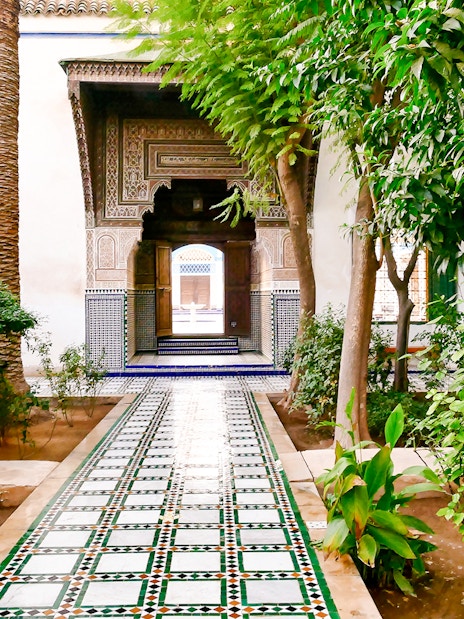 Bahia Palace gardens with tiled pathway and lush greenery in Marrakech, Morocco.